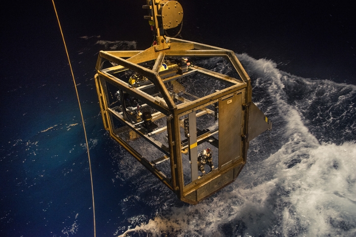 The cage with the camera and hydrophone are raised above the water at night.