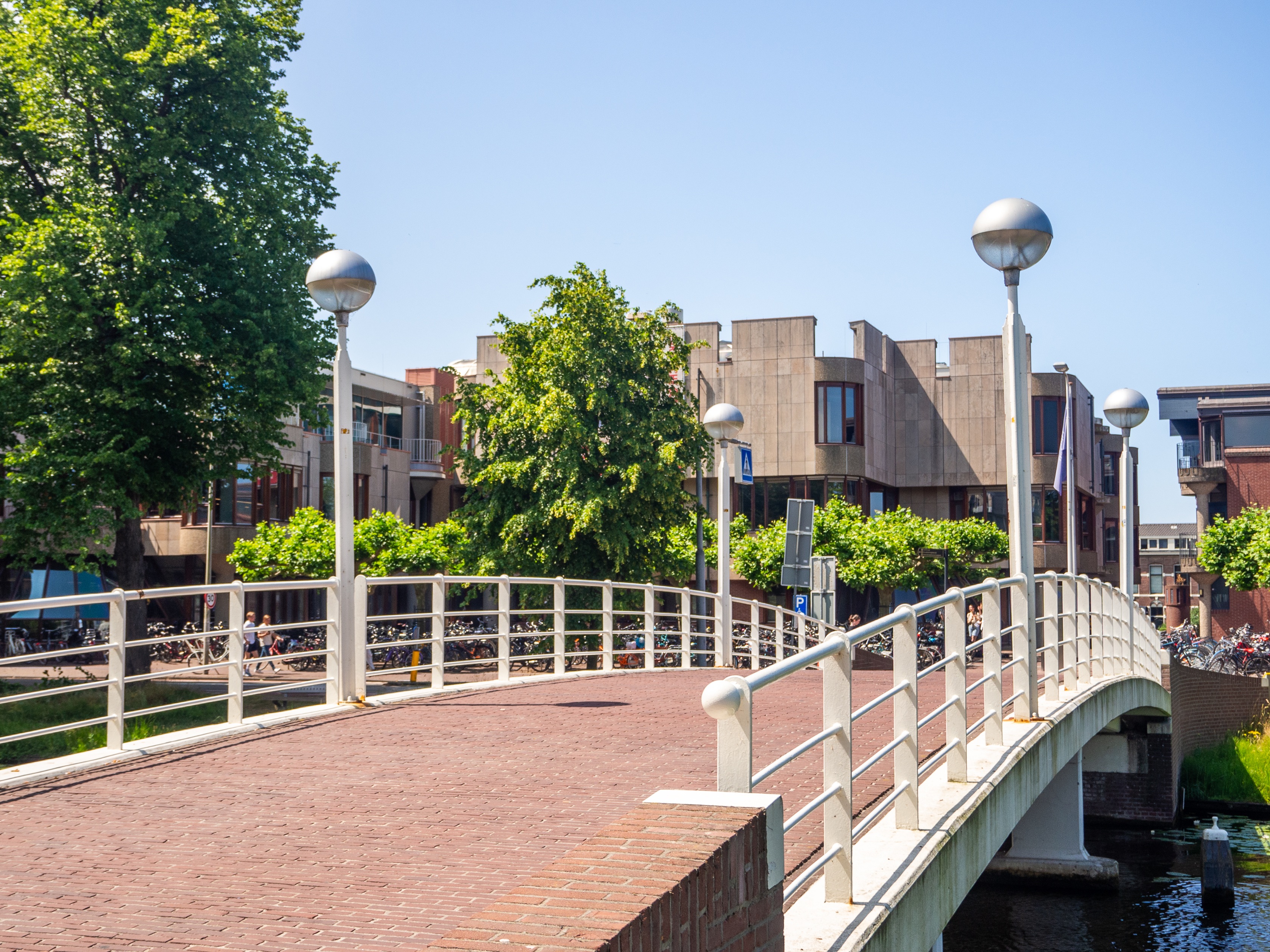 Sunny bridge over canal next to the brick Leiden University Library