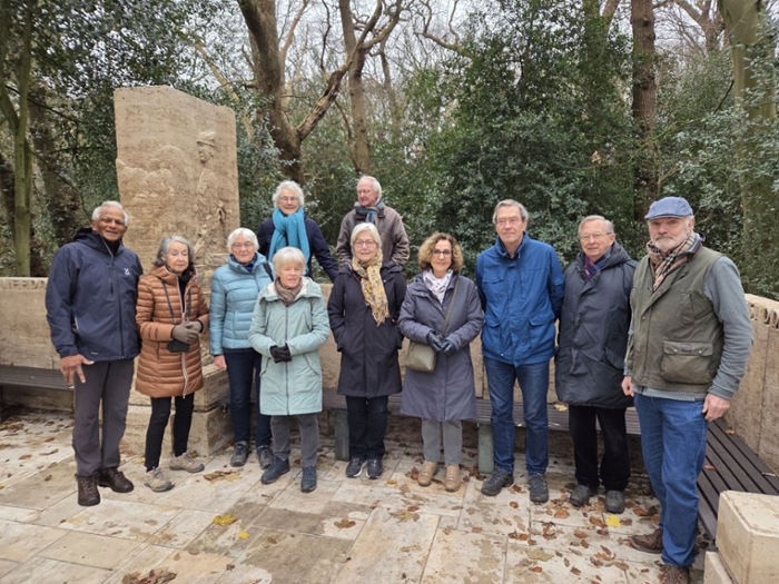Een groep ouderen poseert voor een monument met bankjes