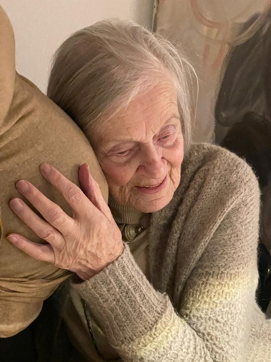 An older woman lays her head on her grandchild’s pregnant belly.