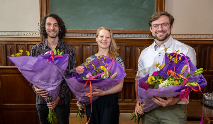 A smiling Katharina Natter with two smiling men with a large bunch of flowers.