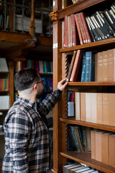 A photo of Ali Kösedag looking at books in the Old Observatory library.