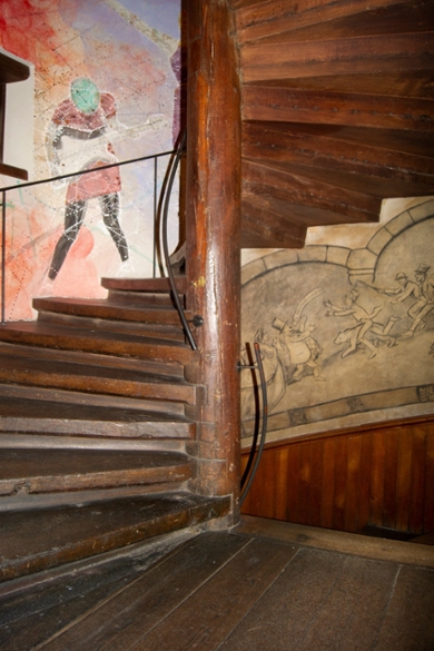 A photo showing the winding staircase in the Academy Building with the drawings by Victor de Stuers and the painting by Adam Uriel.