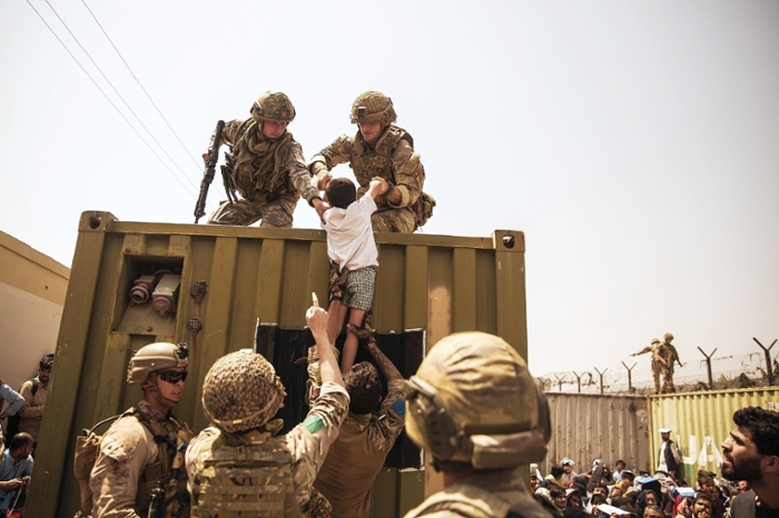 Western military personnel help an Afghan child during the evacuation at Hamid Karzai International Airport, Kabul, on 20 August. Photo: Staff Sgt. Victor Mancilla/Wikimedia