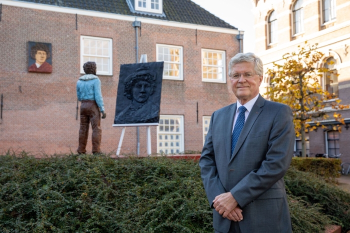 A photo of Bob Wessels standing in front of the statue of young Rembrandt by Stephan Balkenhol.