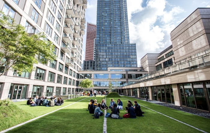 Studenten zitten op het dakterras van het Wijnhavengebouw, het grootste gebouw van de Campus Den Haag van de Universiteit Leiden.