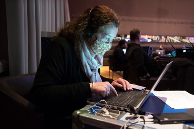 Moderator and art history alumna Hanneke Wiessing wearing a facemask and working at a laptop at the Alumni Office.