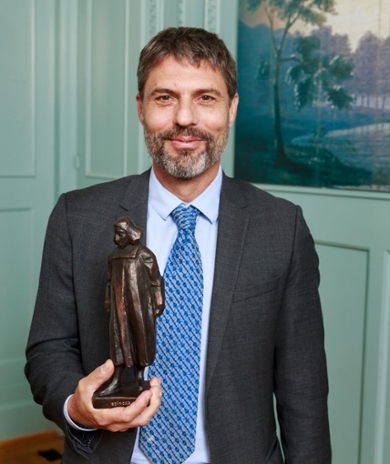 Carsten de Dreu met het bronzen beeld van Spinoza dat bij de premie hoort. (foto: NWO/Bram Saeys)