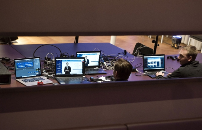 Two men sit at four laptops connected by a tangle of cables ensure that the even goes well.