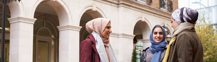 Three young women with a hijab talking and laughing