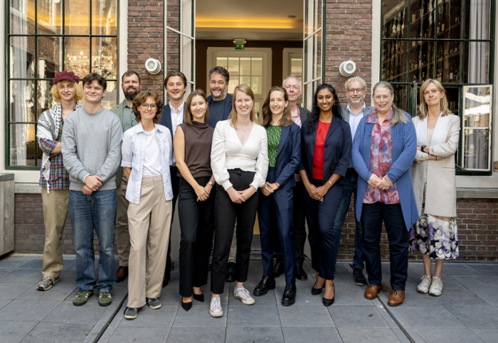 Een groep mensen poseert voor de deur van een gebouw