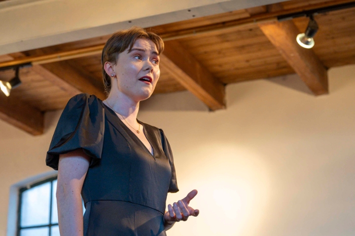 Aimee zingt uit volle borst terwijl ze de zaal inkijkt.