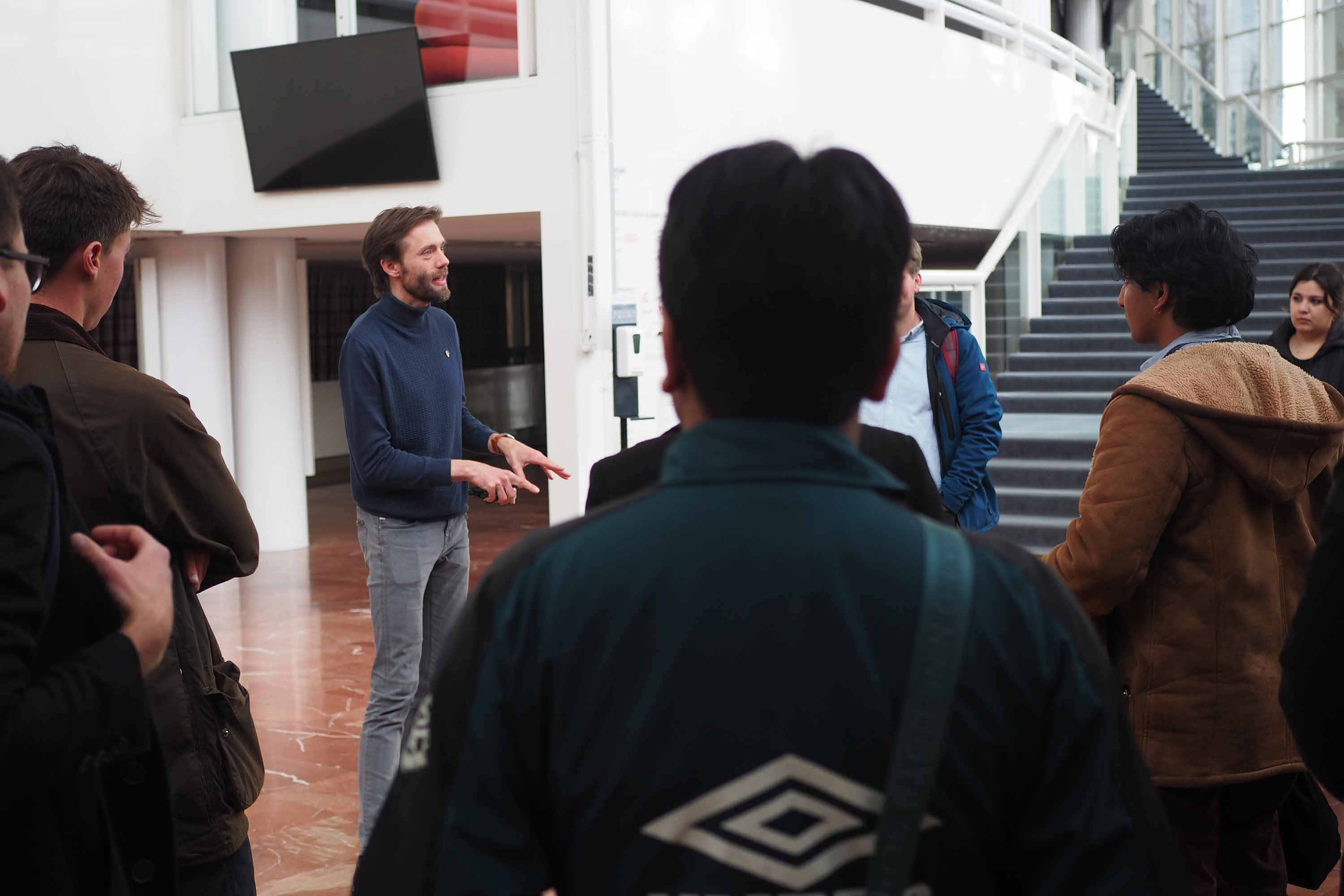 Een medewerker van de Nationale Opera spreekt geanimeerd een groep studenten toe.