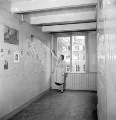 Truus Wijsmuller, board member of the Anne Frank Stichting, removes the plastic covering the pictures in Anne's room before the official opening of the museum. Amsterdam, 3 May 1960. Photo collection: AHF/ Internationaal Instituut voor Sociale Geschiedenis, Amsterdam/ photographer: Ben van Meerendonk