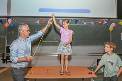 Een man en twee kinderen doen een experiment met een slingerend touw.