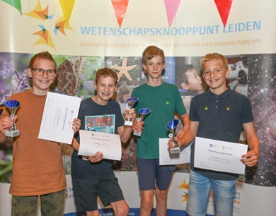 Vier jongens met certificaten en trofeeën
