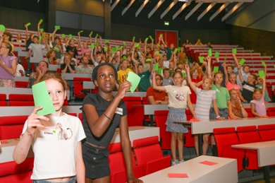Kinderen in een zaal houden groene kaartjes omhoog.