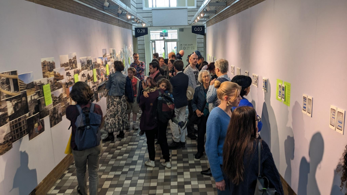 Visitors at the exhibition 'Picturing Scholasticide' in a corridor at Leiden University.