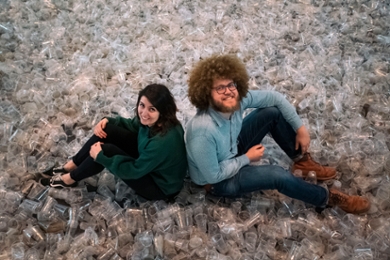 Liselotte Rambonnet en Auke-Florian Hiemstra op een berg verzamelde plastic bekers (foto: Alexander Schippers)