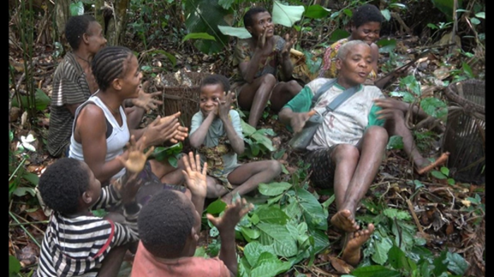 A BaYaka group of women and girls singing and clapping enthusiastically while resting during a hectic day’s work in the forest