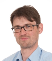 Een jongeman van in de dertig met bril en stoppelbaard.